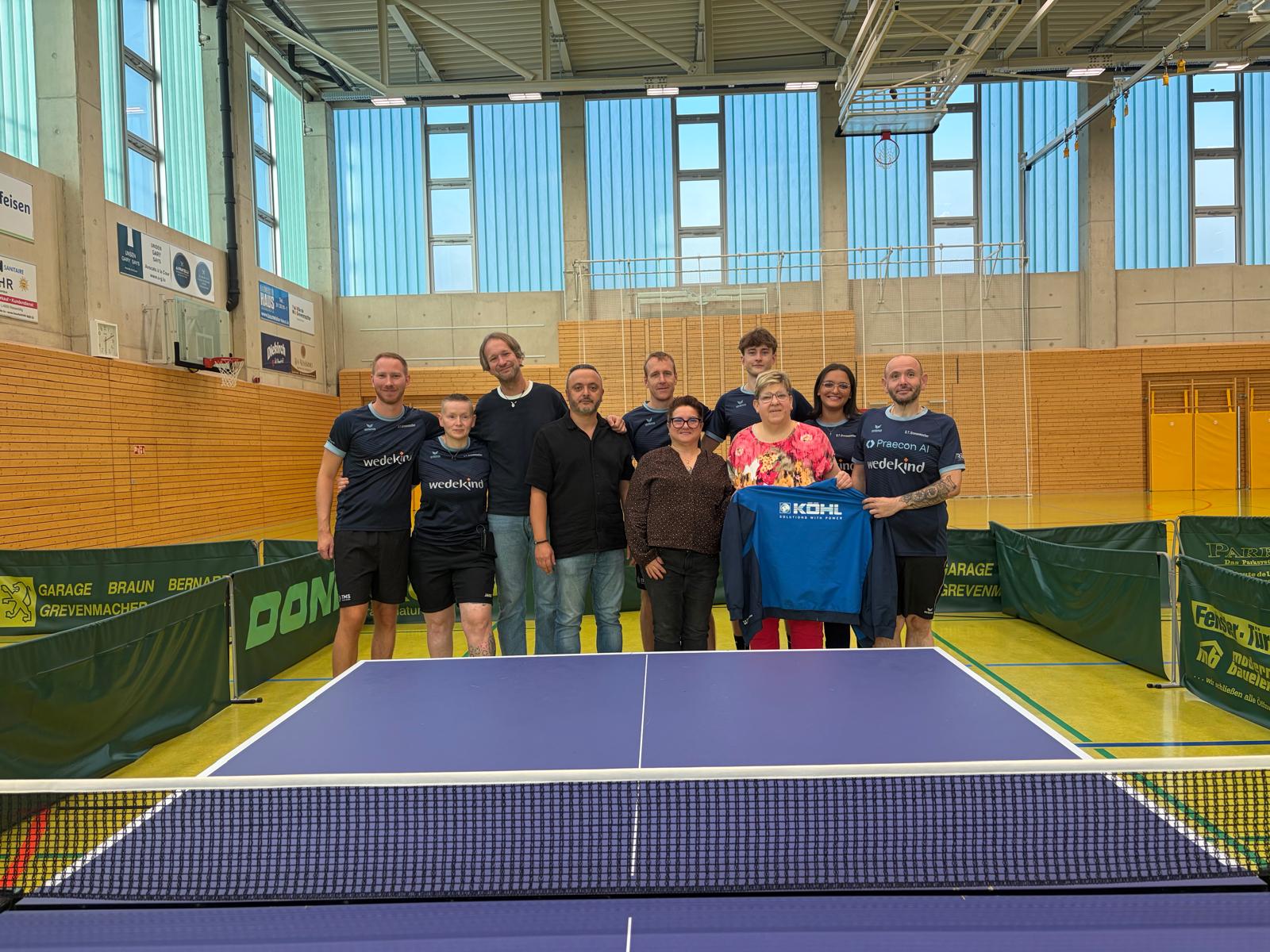 Le comité du Dëschtennis Gréiwemaacher réuni derrière une table de tennis de table dans la salle du club